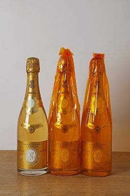 trois bouteilles de champagne posées sur une table l'une à côté de l'autre