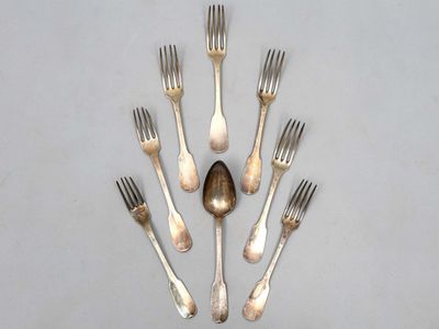 six fourchettes et une cuillère disposées en cercle sur une table