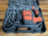 une perceuse électrique orange et noire dans un coffret posé sur une table en bois