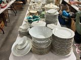 une longue table sur laquelle sont disposées de nombreuses assiettes et bols