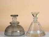 two glass vases sitting on a table with a beige background
