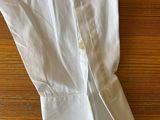 white shirt laying on a wooden table with a knife in it