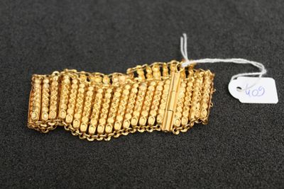 gros plan d'un bracelet en or sur une surface noire