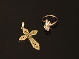 two gold rings and a cross on a black surface
