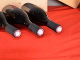 four bottles of wine are lined up on a red table cloth