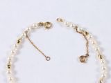 a close up of a necklace with pearls on a white surface