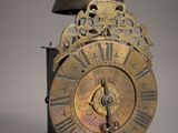 une horloge posée sur un socle, surmontée d'une cloche