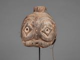 a wooden mask on a stand on a gray background