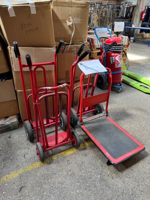 un diable rouge posé à côté d'une pile de cartons