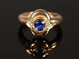 gros plan d'une bague en or avec un saphir et des diamants