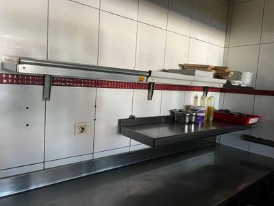 une cuisine équipée de plans de travail en inox et d'une étagère en métal