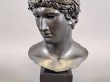 sculpture of a head of a man with curly hair on a wooden base