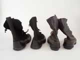 three pairs of black boots are lined up on a white surface