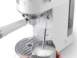 someone is holding a cup of milk in front of an espressor machine