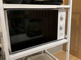 a microwave that is on top of a shelf with plates and bowls
