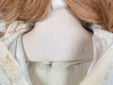 a close up of a doll wearing a white coat