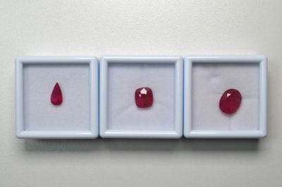 trois pierres précieuses rouges se trouvent dans une boîte blanche posée sur une surface blanche