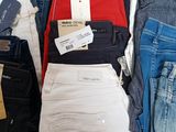 a lot of different colored jeans on display in a store