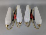 three white and gold wall lights with red accents on them