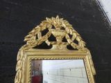 a mirror with a gold frame and a vase on it