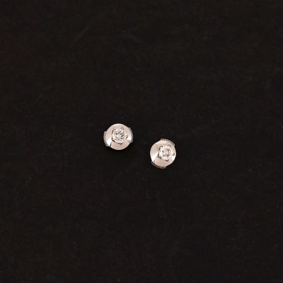 a pair of silver earrings on a black surface