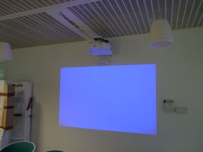 un écran de projection dans une pièce équipée de chaises et d'une table