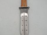 a close up of a knife on a white surface with a measuring stick