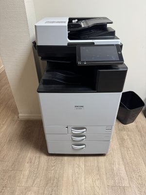 a black and white printer sitting on top of a wooden floor