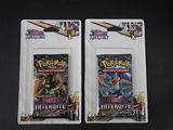 On voit deux paquets de cartes à collectionner Pokémon posés sur une surface noire.