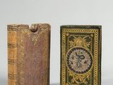 deux livres miniatures posés l'un sur l'autre sur une surface blanche
