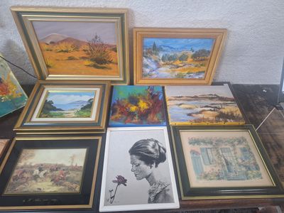 de nombreuses œuvres d'art encadrées posées sur une table dans une pièce