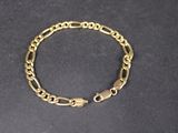 a close up of a gold chain bracelet on a black surface