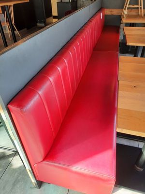 un banc rouge dans un restaurant avec une table et des chaises en bois