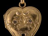 un pendentif ancien en forme de cœur doré, orné d'un diamant noir en son centre