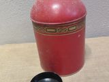 a red vase with a black lid sitting on a table