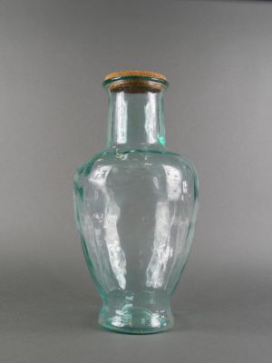 un vase en verre muni d'un couvercle en bois, posé sur une table