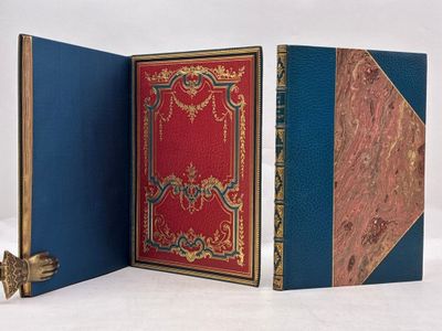 Trois livres sont ouverts sur une surface blanche ; l'un est rouge et l'autre est bleu