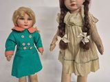 two dolls are standing next to each other on a white surface
