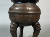 a large bronze pot on a stand with two legs
