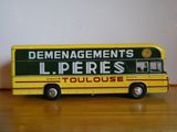 un petit bus jouet jaune et vert posé sur une table en bois