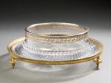 a silver and gold plate with a glass bowl on top of it