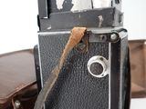 a black camera with a brown strap and a brown case