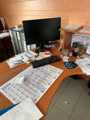 a desk with a computer, keyboard, monitor, and papers on it