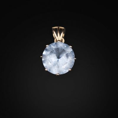 un pendentif en or orné d'une topaze bleue sur fond noir