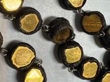 a necklace made of black and gold beads on a table