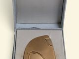 a small gold object in a box on a white surface
