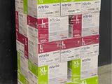 des cartons empilés sur une palette devant un mur noir