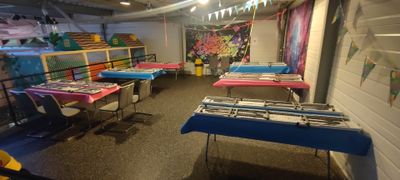 a room with many tables and chairs with colorful cloths on them