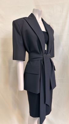 the woman is wearing a black dress and jacket with a belt