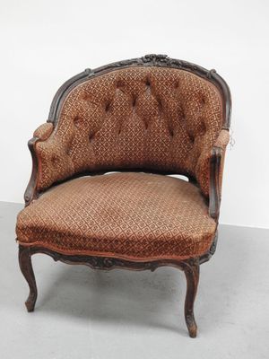 une vieille chaise dont l'assise et le dossier sont recouverts de tissu marron